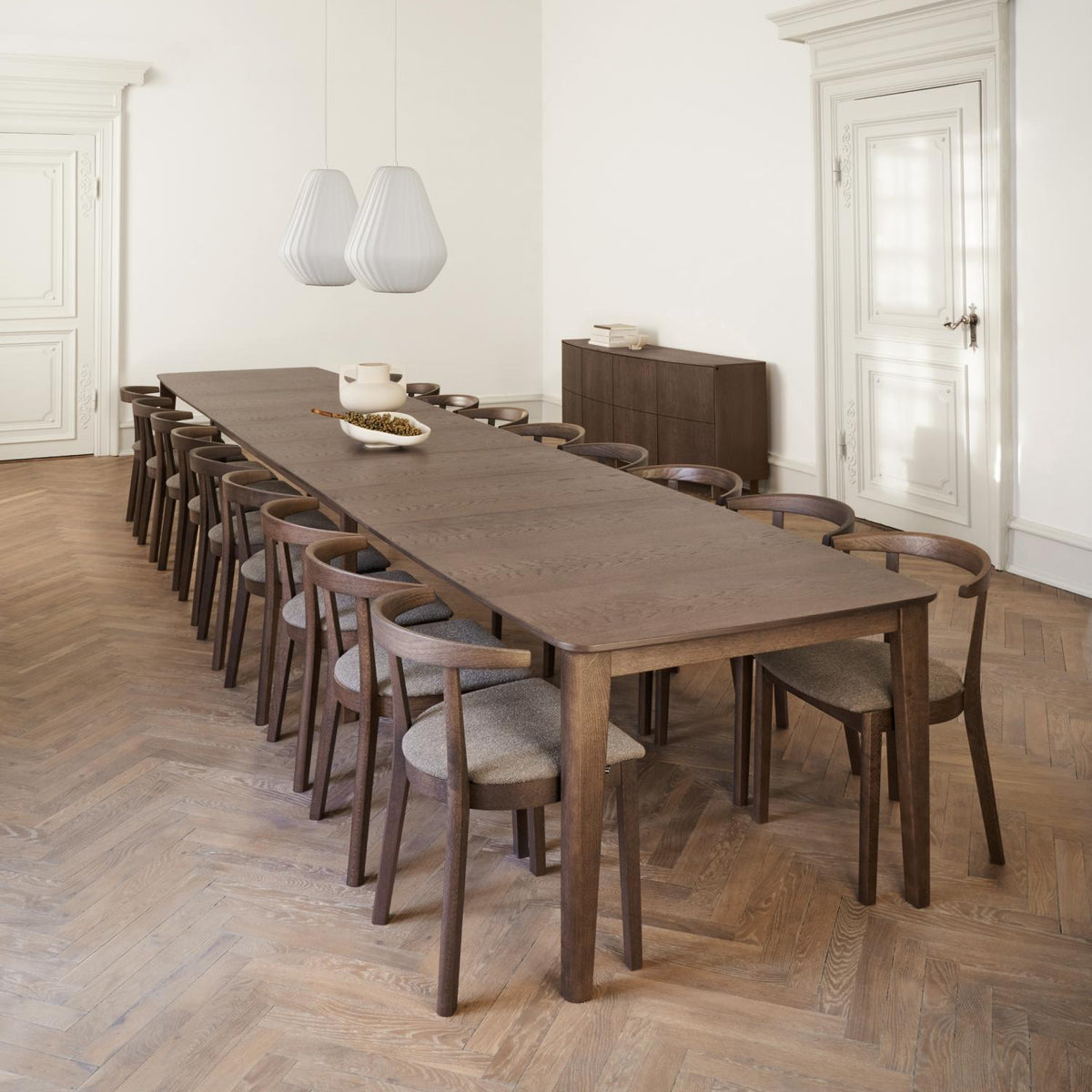 Long wooden dining table with chairs in a minimalistic room.