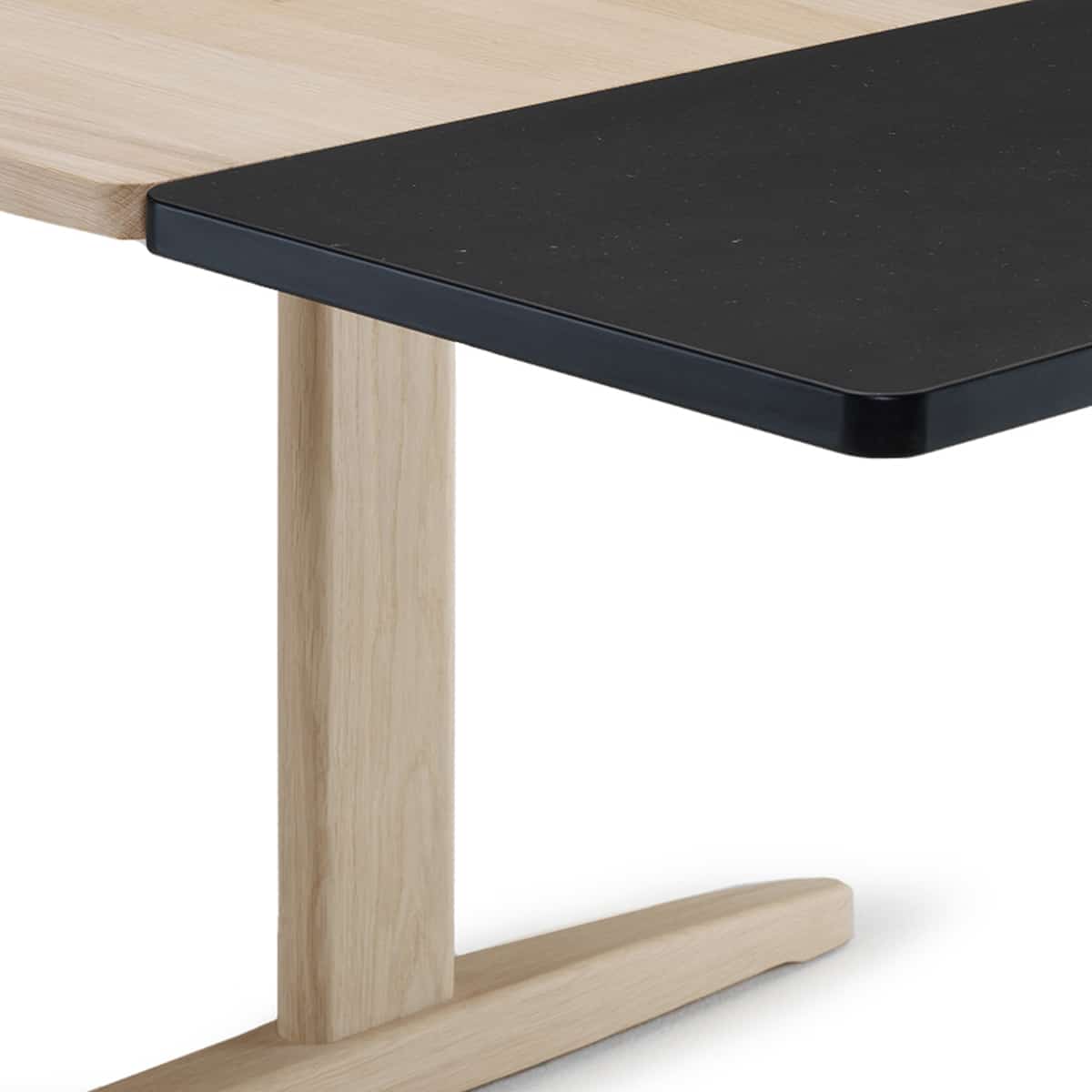 Close-up of a modern table with a black rectangular  extension leaf and a light natural wood T-style leg on a white background.