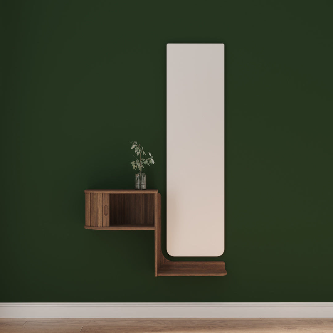 A modern wall-mounted mirror with a tall, rectangular white frame, paired with a floating L-shaped wooden shelf in a dark green room.