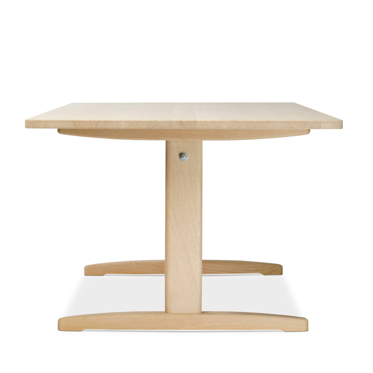 A light natural wood dining table with a square top, central pedestal base, and curved apron details, shown against a plain white background.