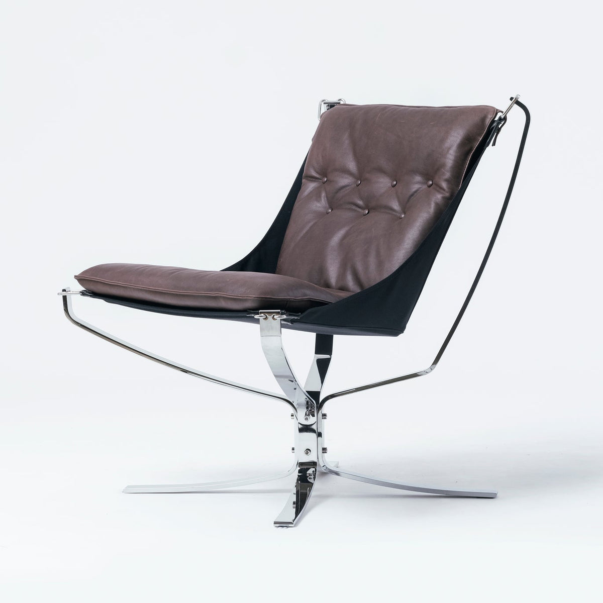 A modern lounge chair with a brown tufted leather seat and backrest, supported by a black fabric sling and a chrome star base, photographed against a seamless white background.