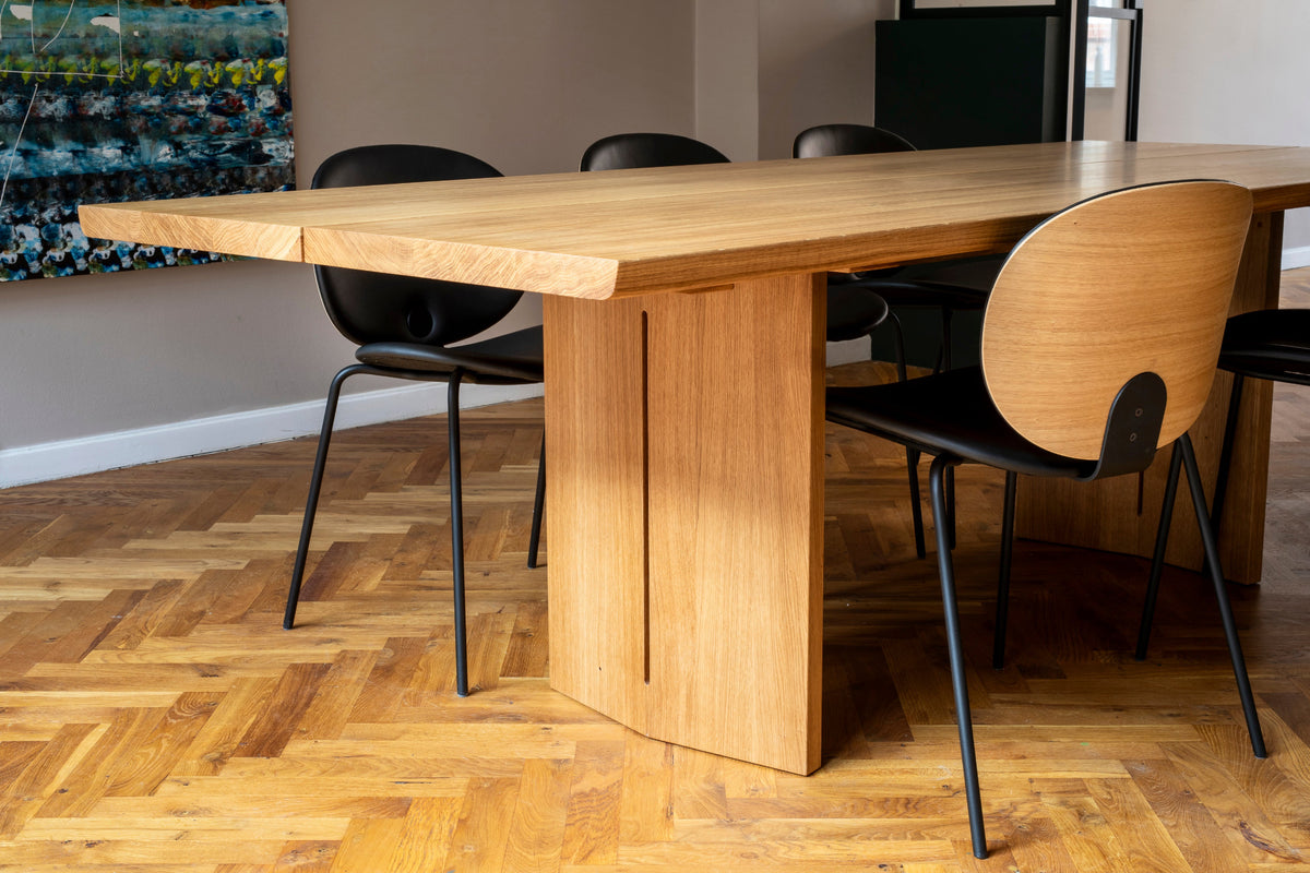Wooden dining table with black chairs on a wooden floor