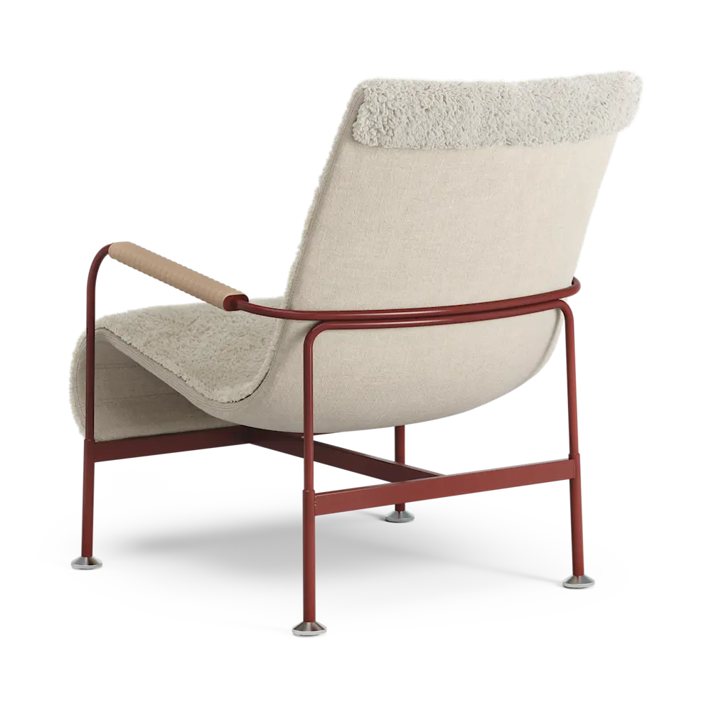 A modern lounge chair with cream bouclé upholstery, a reddish-brown metal frame, and a light wood armrest, shown from a three-quarters angle on a white background.